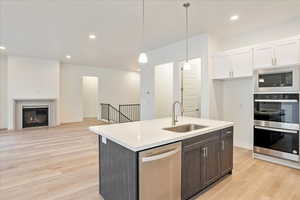 Kitchen featuring appliances with stainless steel finishes, light hardwood / wood-style flooring, white cabinetry, and sink