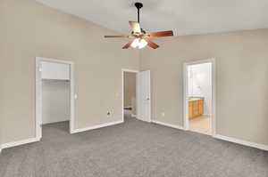 Unfurnished bedroom with a spacious closet, ensuite bath, a closet, light carpet, and ceiling fan