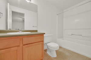 Full bathroom featuring vanity, washtub / shower combination, toilet, and tile patterned floors