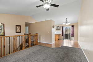 Unfurnished room with light hardwood / wood-style flooring, ceiling fan with notable chandelier, and lofted ceiling