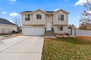 Raised ranch featuring a garage and a front lawn