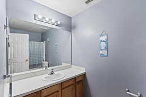 Bathroom with vanity, a textured ceiling, and toilet