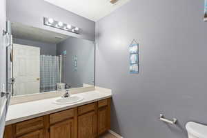 Bathroom featuring vanity, a textured ceiling, and toilet