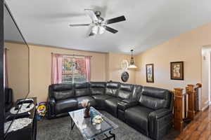 Living room with lofted ceiling, dark wood-type flooring, and ceiling fan