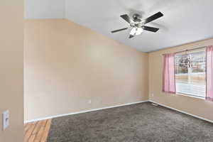 Spare room with hardwood / wood-style floors, ceiling fan, and lofted ceiling