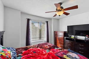 Bedroom with a textured ceiling and ceiling fan