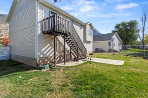 Rear view of house with a wooden deck and a lawn