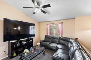 Carpeted living room featuring vaulted ceiling and ceiling fan