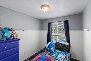 Bedroom with a textured ceiling and wooden walls