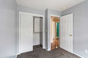 Unfurnished bedroom featuring a closet and dark carpet