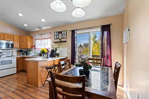 Kitchen with white electric range oven, kitchen peninsula, pendant lighting, and dark hardwood / wood-style floors