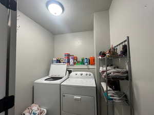 Laundry room featuring washer and dryer and a textured ceiling