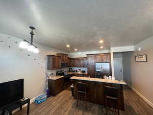 Kitchen featuring stainless steel appliances, decorative light fixtures, a kitchen island, and dark hardwood / wood-style flooring