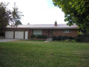 Ranch-style house featuring a front lawn and a garage