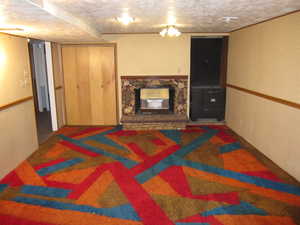 Basement with a stone fireplace and a textured ceiling