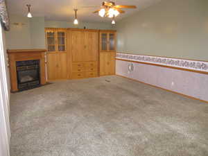 Unfurnished living room with a high end fireplace, carpet flooring, and ceiling fan