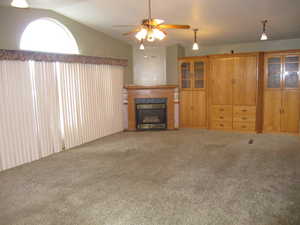 Unfurnished living room featuring vaulted ceiling, carpet floors, and ceiling fan