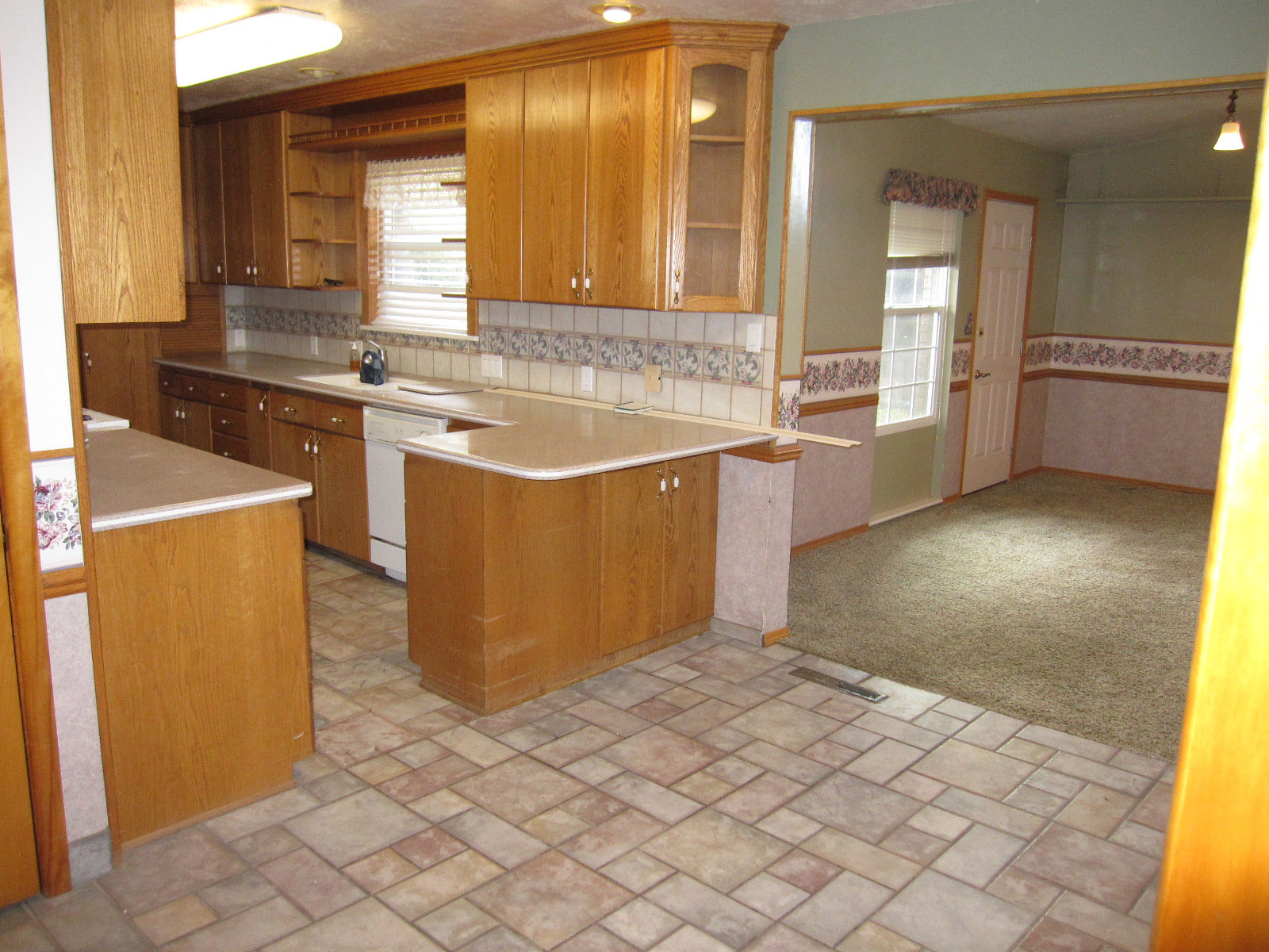 Kitchen featuring dishwasher, kitchen peninsula, backsplash, sink, and light colored carpet