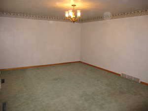 Unfurnished room with an inviting chandelier and carpet flooring