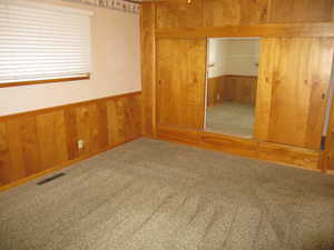 Unfurnished bedroom featuring wood walls and carpet floors