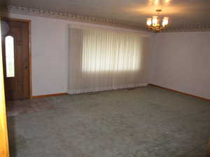 Spare room with a healthy amount of sunlight, carpet flooring, and an inviting chandelier