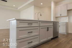 Kitchen with tasteful backsplash, a center island, sink, and dark hardwood / wood-style flooring