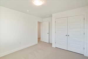 Unfurnished bedroom with a closet and light carpet