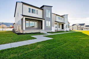 View of front of home with cooling unit and a front yard