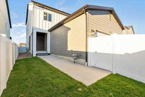 Back of house with a patio area and a lawn