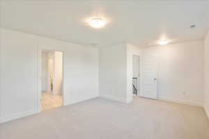 Empty room featuring light carpet and a textured ceiling