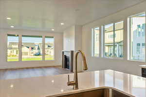 Kitchen featuring hardwood / wood-style floors, a healthy amount of sunlight, light stone counters, and sink