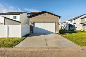 View of front facade featuring a front lawn and a garage