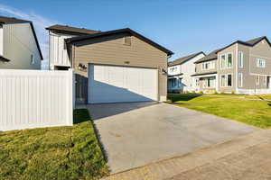 View of front of property featuring a garage and a front lawn