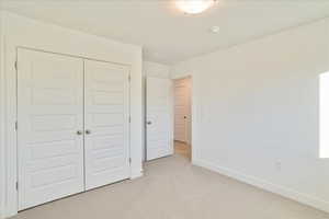 Unfurnished bedroom with a closet and light colored carpet