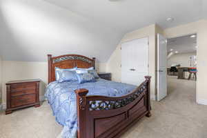 Bedroom with light carpet and lofted ceiling