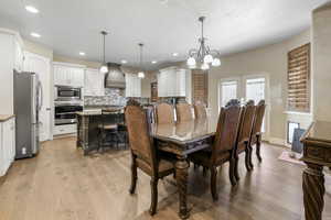 Dining room with light hardwood / wood-style flooring and a notable chandelier