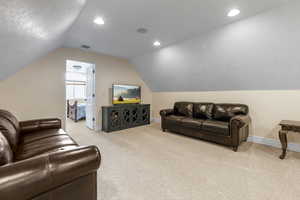 Living room with lofted ceiling and light carpet