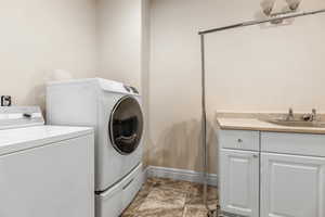 Laundry area featuring cabinets, sink, and washer and dryer