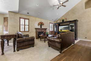 Living room with hardwood / wood-style floors, ceiling fan, and high vaulted ceiling