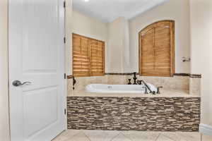 Bathroom with a tub to relax in and tile patterned floors