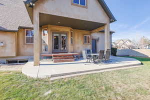 Back of house with french doors, a patio area, and a lawn