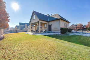 Back of house with a patio and a lawn