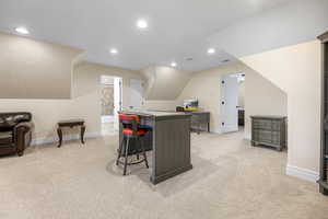 Office space featuring light colored carpet and vaulted ceiling