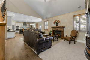 Living room with light wood-type flooring, high vaulted ceiling, and a chandelier