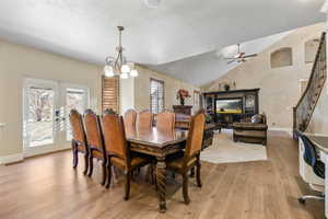 Dining area featuring french doors, light hardwood / wood-style floors, a textured ceiling, vaulted ceiling, and ceiling fan with notable chandelier