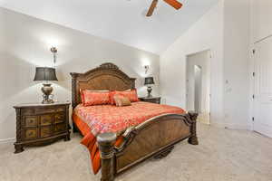 Carpeted bedroom featuring ceiling fan and lofted ceiling