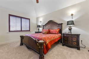 Carpeted bedroom featuring ceiling fan and lofted ceiling