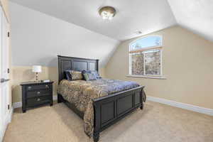 Bedroom with a textured ceiling, light carpet, and vaulted ceiling