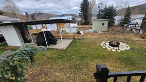 View of yard with a mountain view, a storage shed, and a fire pit