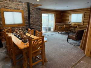 Carpeted dining space featuring a wood stove and rustic walls